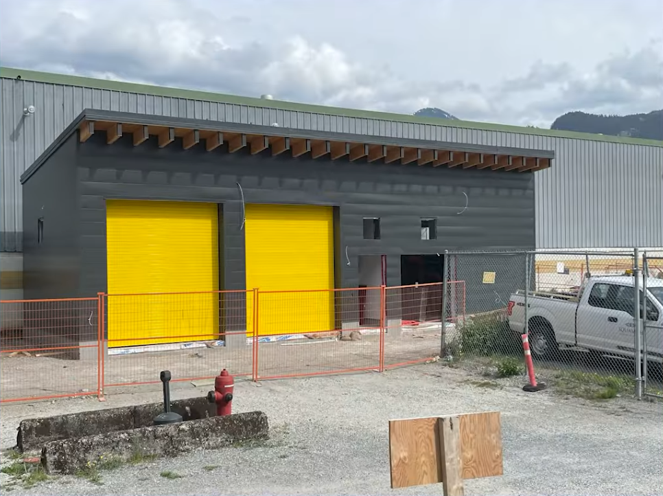 Construction site with a grey building and bright yellow doors, part of the Brennan Park Recreation Centre renovation project.
